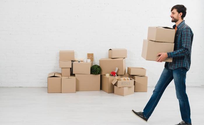 Boxes, Beginnings, And What Moving Really Means side view young man carrying cardboard boxes hand walking room 23 2148095493